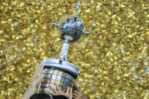 A person holding a trophy in front of a wall of confetti