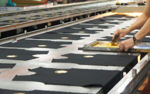 a person cutting fabric on a conveyor belt