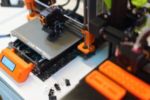 An orange and black 3D printer sitting on top of a table